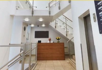 Modern reception area featuring a wood-paneled desk and sleek white staircase.