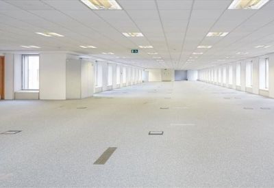 Bright, expansive open-plan office floor with recessed lighting and many windows.
