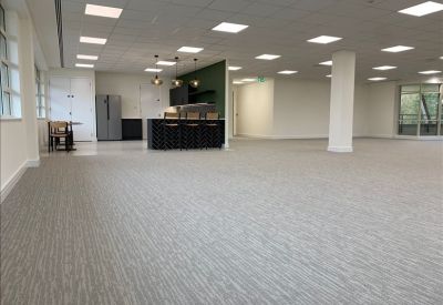Expansive open-plan office area featuring a modern kitchen island and neutral carpet.