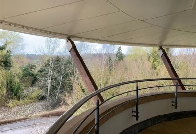 Curved balcony view looking out over lush green trees and a wooded landscape.