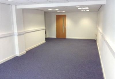 Spacious open-plan internal office suite with blue carpeting and white walls.