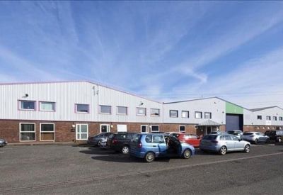 Wide exterior view of the commercial building facade with multiple parking spaces in front.