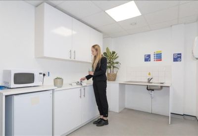Communal kitchen area with white cabinetry, a microwave, and a small potted plant.