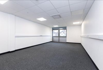 Spacious empty office suite with white walls, grey carpet, and bright LED panel lighting.