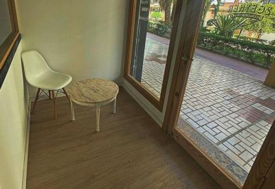 Bright reception waiting area with wooden floors, a white chair, and glass doors.