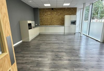 Spacious open-plan kitchen and dining area with wood-effect flooring and a brick feature wall.