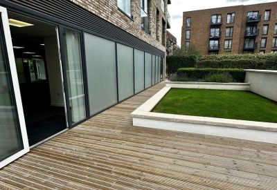 Spacious timber-decked rooftop terrace with a raised lawn area and brick building facade.