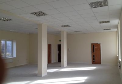 Spacious office interior with natural light from large windows and a wooden door.