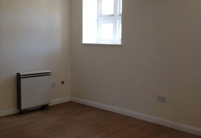 Private office space with wood-effect flooring, a wall heater, and an exposed timber ceiling beam.