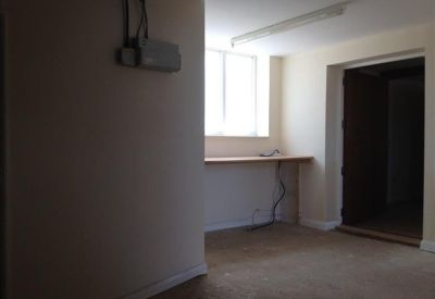 Small office nook with a built-in work surface under a bright window and neutral walls.