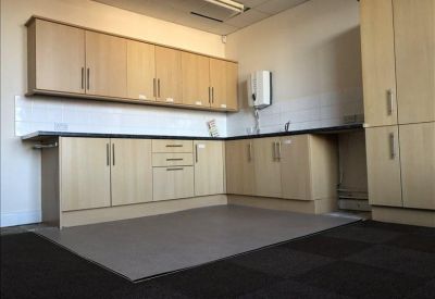 Communal kitchen area with light wood cabinetry and dark countertops.