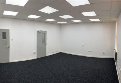 Large open-plan office suite with dark carpeting and bright recessed ceiling lights.