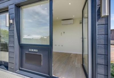 Interior of a modern private office suite featuring wood-effect flooring and a glass entrance door.