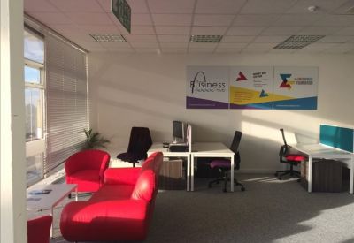 Coworking space featuring red sofas, white desks, and large wall graphics.