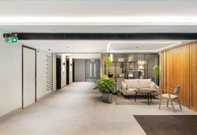 Bright corridor and lounge area featuring a plush sofa, wooden accents, and indoor greenery.