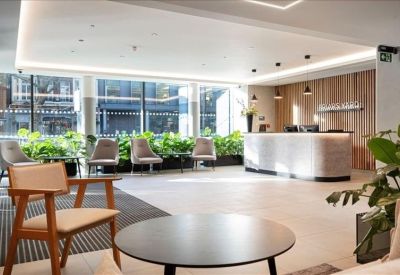 Modern reception lobby with a white curved desk, warm wood paneling, and indoor plants.