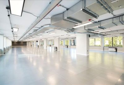Spacious open-plan office space with polished floors and exposed ceiling ductwork.