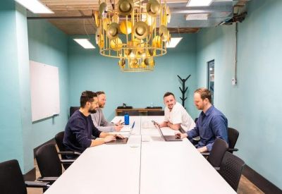 Turquoise meeting room with a large white table and a unique circular gold chandelier.