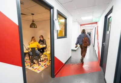 Modern office hallway with vibrant red geometric wall patterns and glass-fronted suites.