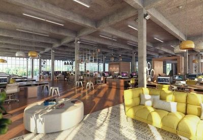 Industrial-style office with concrete pillars, warm wood floors, and yellow sofas.
