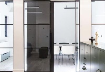 Glass-walled meeting room with industrial black frames and a white conference table.
