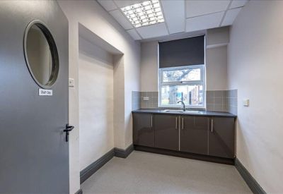 Small kitchenette area with dark grey cabinetry and a stainless steel sink.