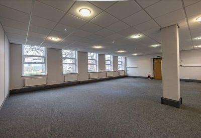 Large open-plan office space with grey carpeting and a supporting pillar.
