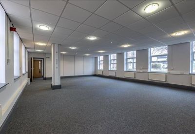 Spacious empty office room with multiple large windows and ceiling lights.