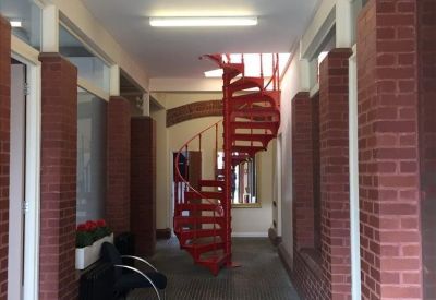 Bright hallway featuring a striking red spiral staircase and exposed brick pillars.