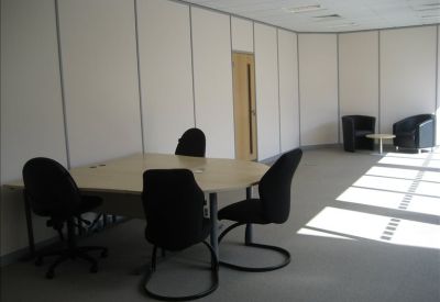 Private office space with a light wood desk and black ergonomic chairs.