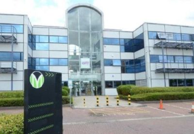 Main entrance with glass atrium and branded black signage pedestal.
