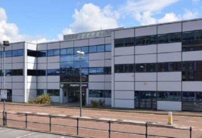 Side view of a three-story commercial building with light gray cladding.