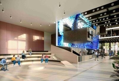 Modern lobby with a massive blue digital screen and stadium-style wooden seating.