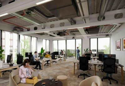 Light-filled open-plan office with multiple rows of desks and large floor-to-ceiling windows.