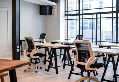Bright open-plan workspace featuring several white desks and ergonomic mesh chairs.