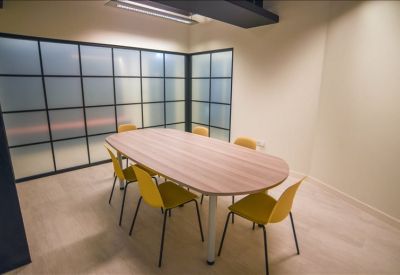 Contemporary meeting room with an oval wooden table and vibrant yellow chairs.