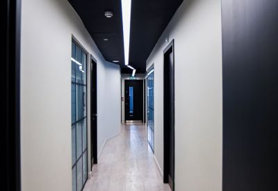 Long modern hallway with white walls, black ceiling, and integrated strip lighting.