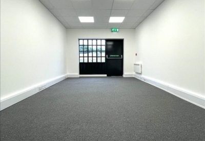 Bright, empty open-plan office suite with grey carpeting.