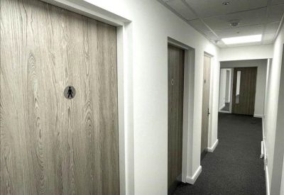 Clean white corridor featuring wood-grain doors and grey carpet.