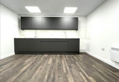 Modern kitchenette and dining area with dark cabinetry and wood-effect flooring.