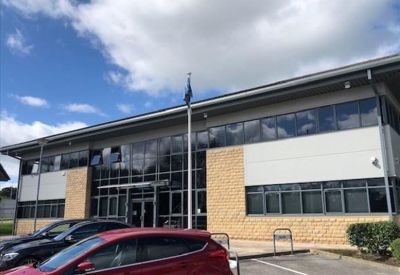 Glass entrance facade and paved parking area.