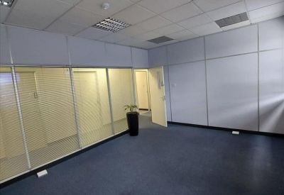 Modern office interior with glass partitioning and a potted plant.