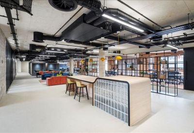 Spacious communal breakout area with a central island bar and industrial ceiling detailing.