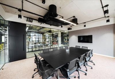 Professional meeting room with a large black conference table and glass walls.