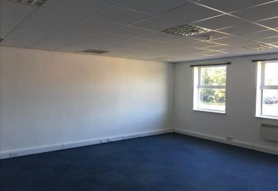 Spacious open-plan office with deep blue carpeting and a suspended tile ceiling.