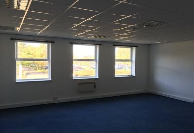 Corner office space with bright white walls and three windows overlooking the grounds.