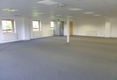Spacious open-plan office suite with grey carpeting and white pillars.