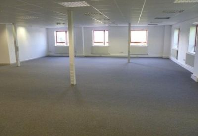 Bright open-plan workspace with multiple large windows and white walls.