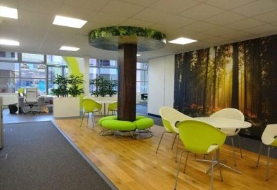 Bright breakout space featuring a tree-trunk pillar, lime green seating, and a forest wall mural.