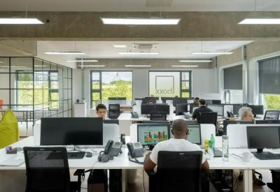 Bright workspace with multiple computer monitors and large windows.